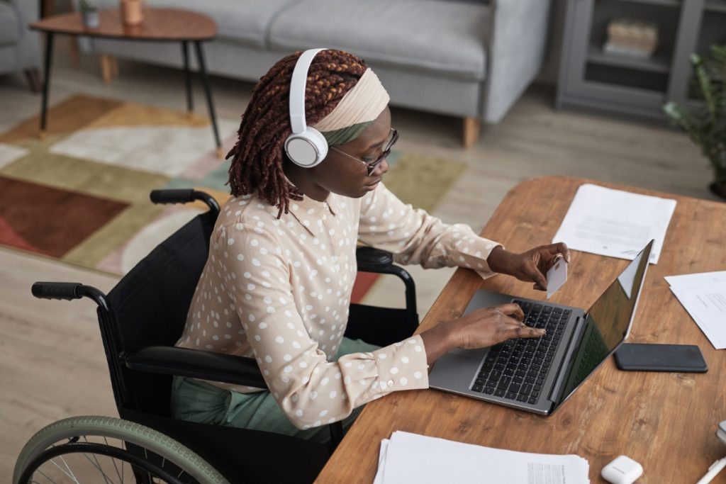 A woman in a wheelchair using a laptop, emphasizing the need for web accessibility for users with disabilities.